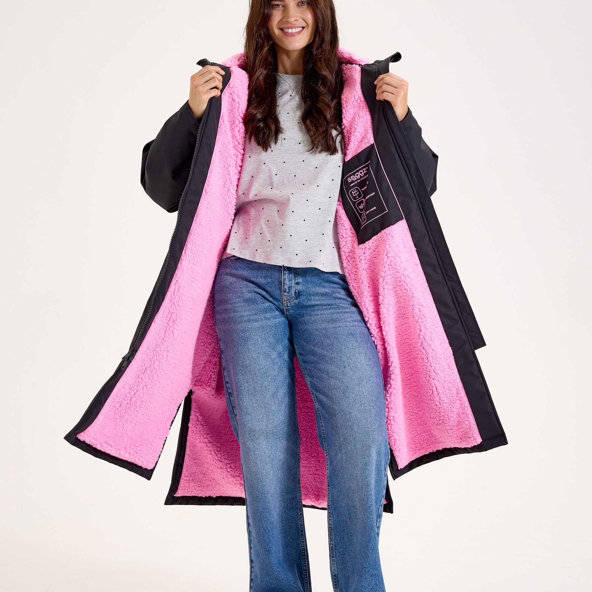 Woman wearing a long black and pink coat on a white background
