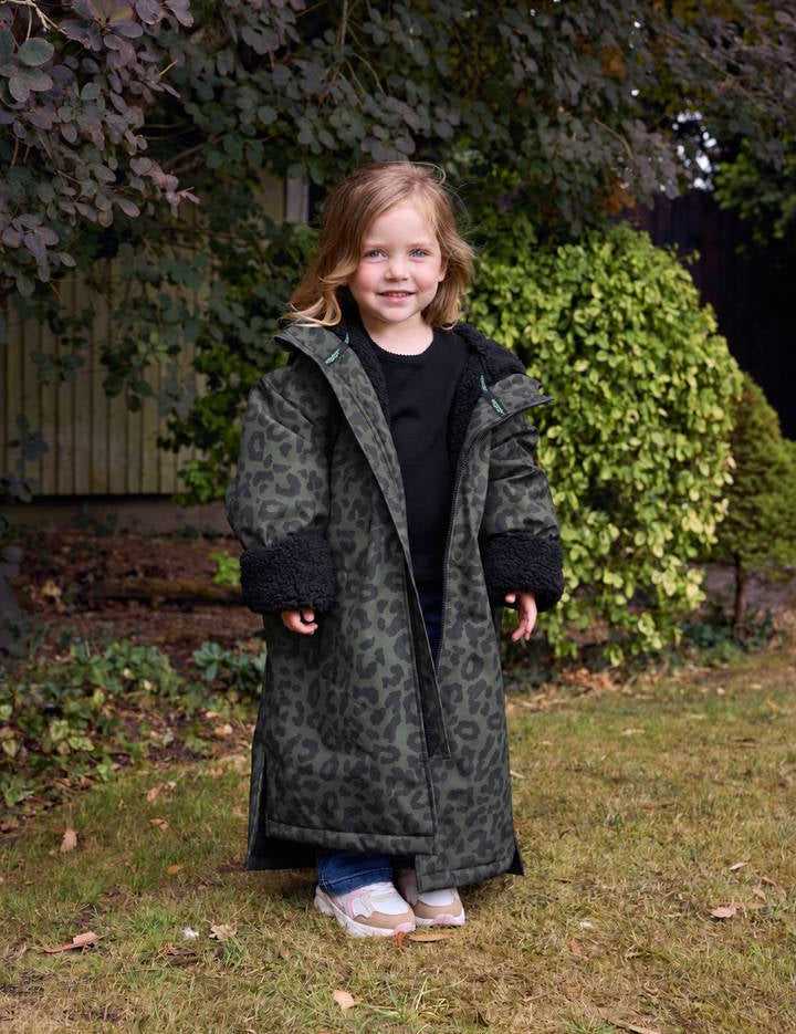 Girl in a garden wearing the Snuggz kids khaki leopard print changing robe